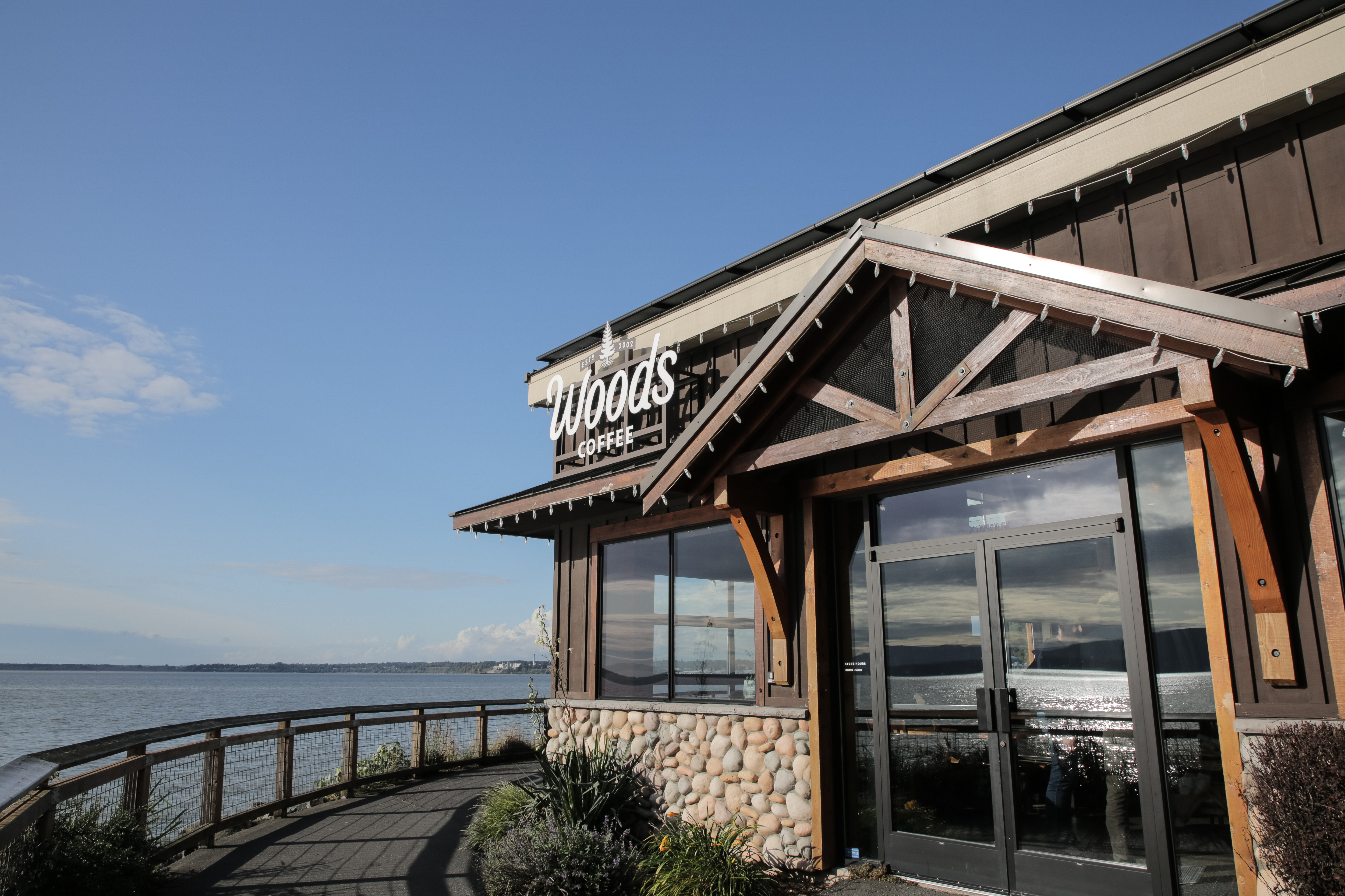 A photograph of the entrance to the Boulevard Park Woods Coffee location with Bellingham Bay in the background.