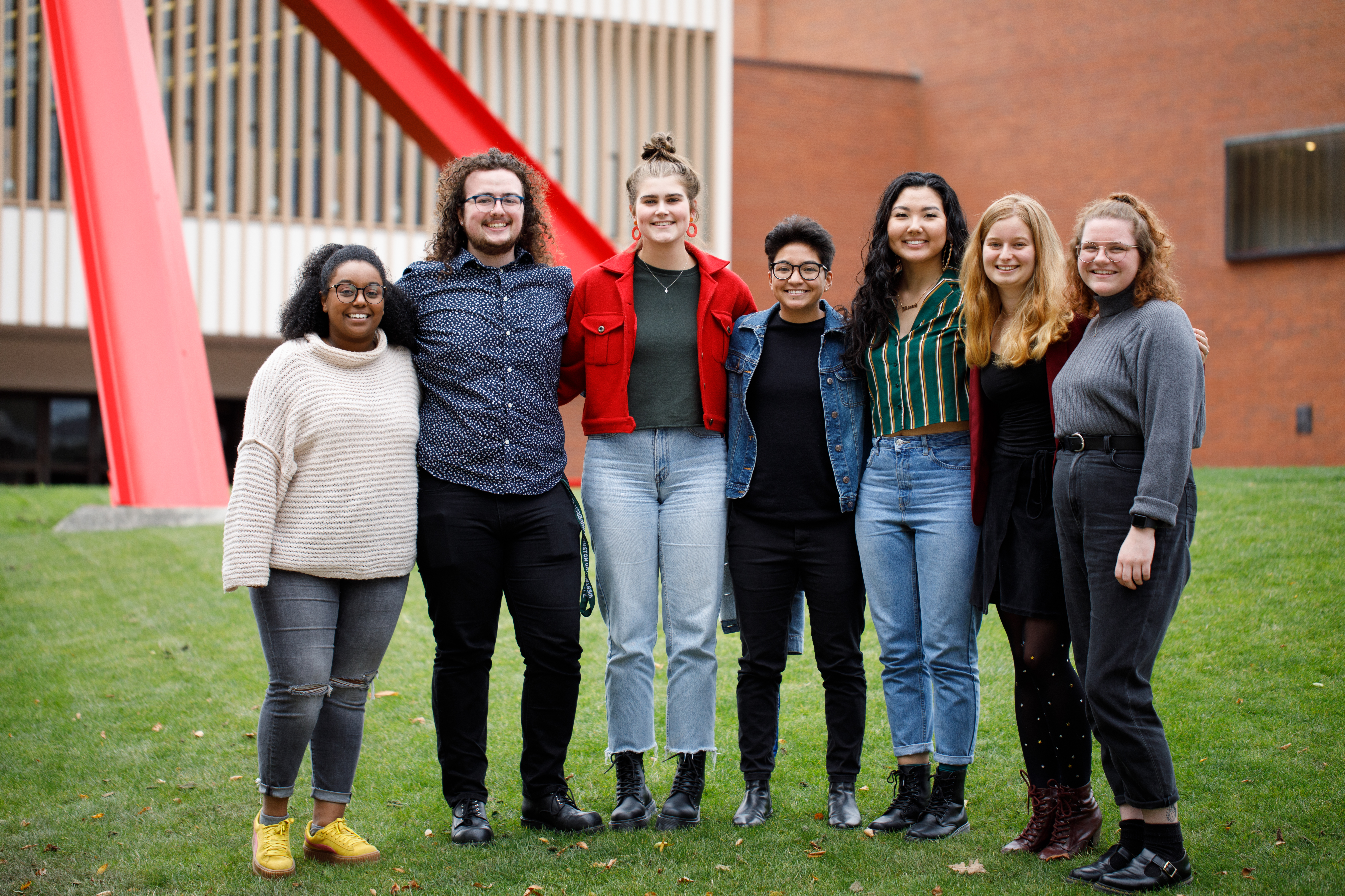 AS Board members: Selome Zerai, Trever Mullins, Grace Drechsel, Lani Defiesta, Yesugen Battsengel, Adah Barenburg and Emily Gerhardt stand in front of the Performing Art Center green space, smiling for their group photo.
