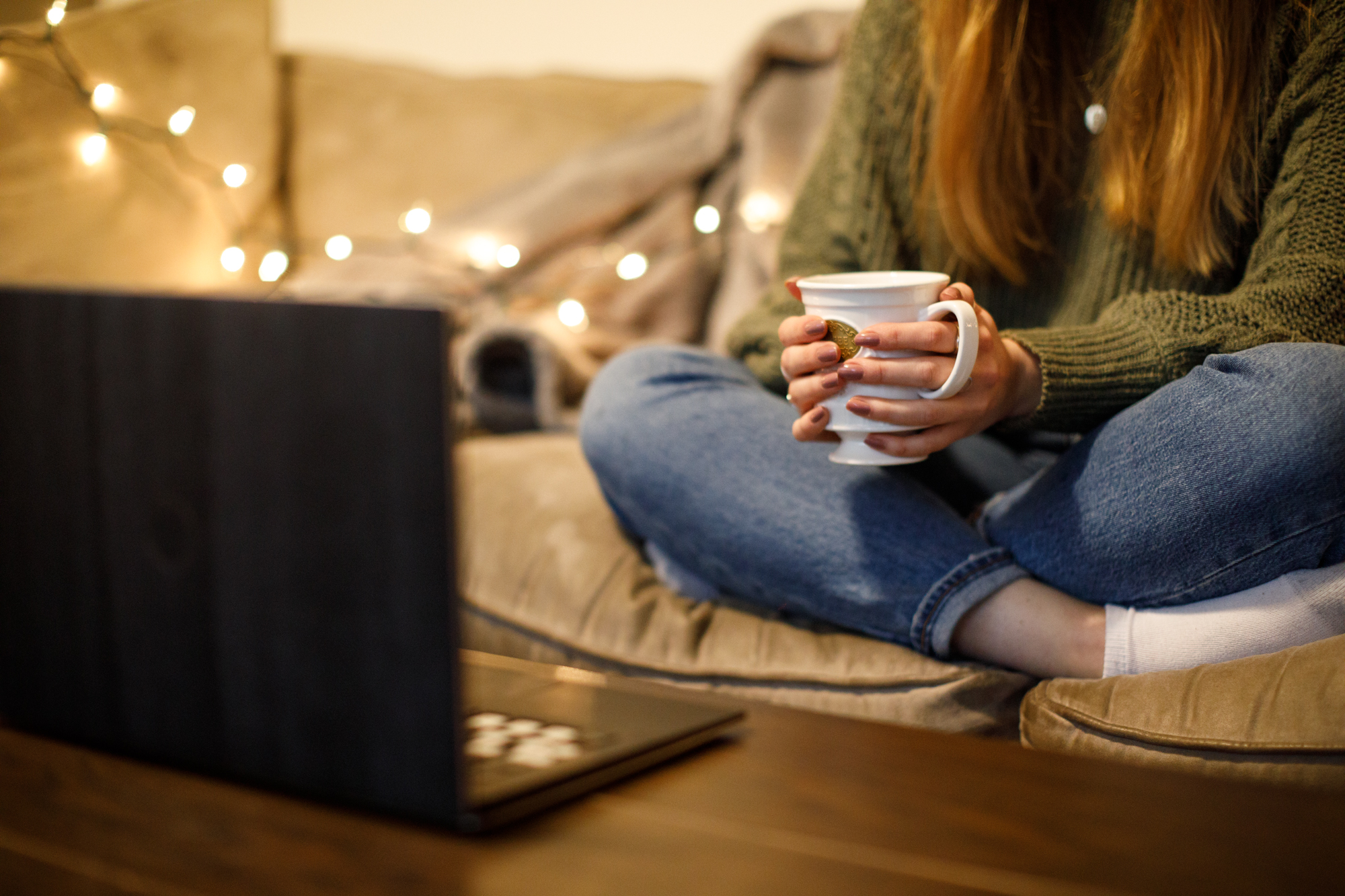 Image of a student watching a movie on their laptop with a mug in their hands.