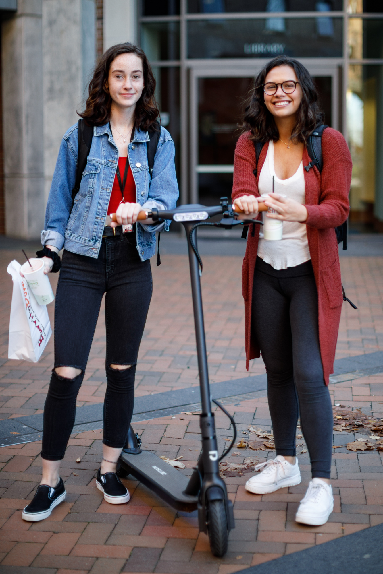 Anya Hyra, left and Kyra Asher, right holding an electric scooter between them.
