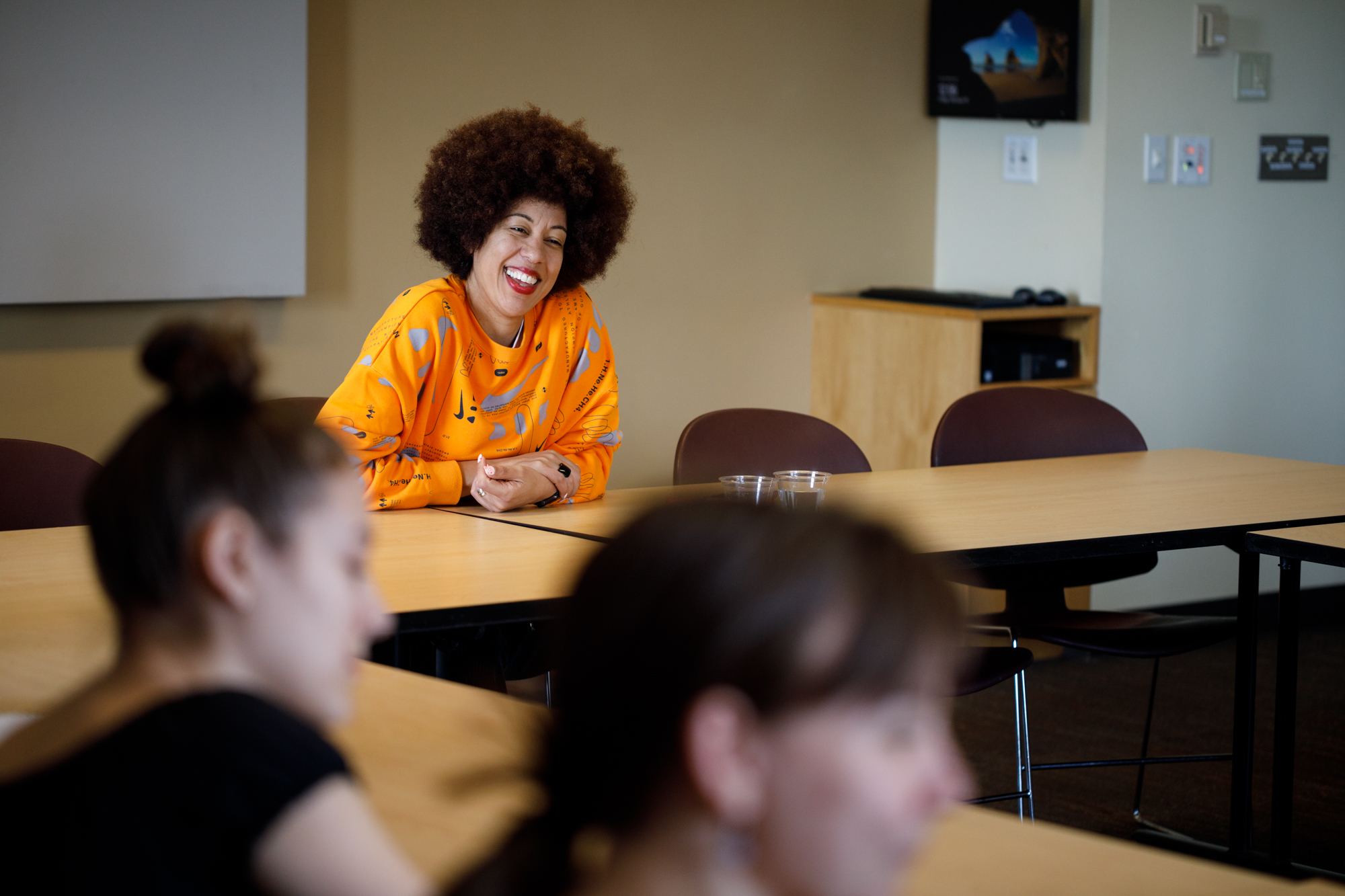 Erin Jones in the center of the frame laughs with a student in the audience off camera.