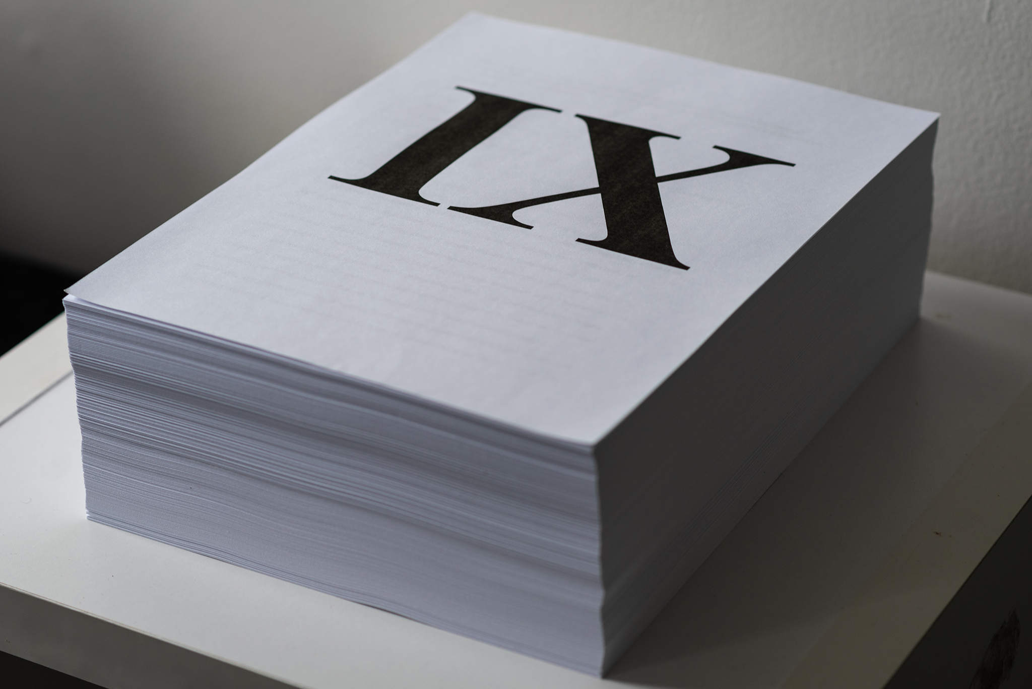 Photographic image of a large stack of paper approximately 1000 sheets high, the top sheet has a large Roman numeral "IX" representing the Title IX documents.